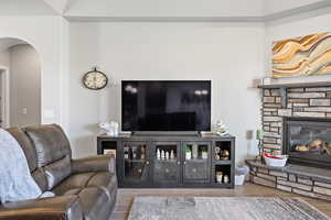 Living area featuring arched walkways, a fireplace, and wood finished floors