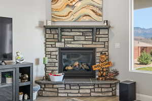 Detailed view of wood finished floors, a fireplace, a mountain backdrop, and baseboards