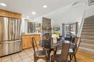 Dining room with a wall unit AC, stairway, a fireplace, high vaulted ceiling, and recessed lighting