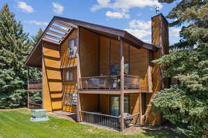 Back of house with a chimney, a balcony, and a yard