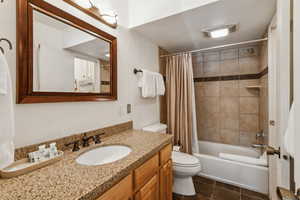 Bathroom featuring toilet, vanity, shower / tub combo, and tile patterned floors