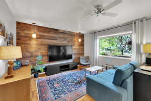 Living room featuring wood walls and ceiling fan