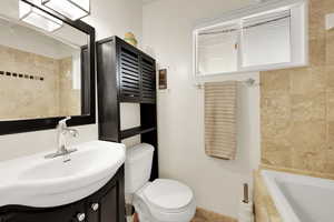 Full bath with tiled tub, vanity, and toilet
