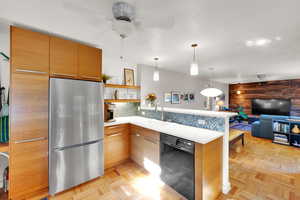 Kitchen with freestanding refrigerator, black dishwasher, a sink, a peninsula, and a ceiling fan