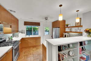 Kitchen with appliances with stainless steel finishes, open shelves, backsplash, hanging light fixtures, and light countertops