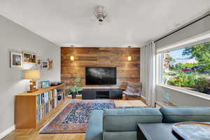 Living room with ceiling fan, baseboards, and wooden walls