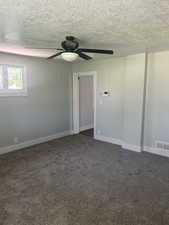 Unfurnished room with a ceiling fan, dark colored carpet, a textured ceiling, and baseboards