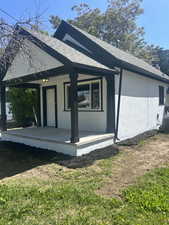 View of side of home featuring covered porch, roof with shingles, stucco siding, and cooling unit