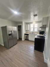 Kitchen featuring stainless steel fridge with ice dispenser, baseboards, a sink, wood finished floors, and light countertops
