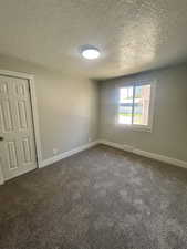 Carpeted empty room with baseboards and a textured ceiling
