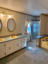 Full bath with a stall shower, double vanity, carpet floors, a textured ceiling, and ornamental molding