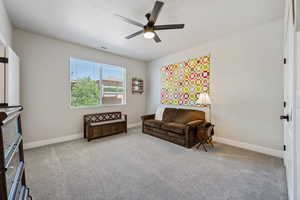Living area with ceiling fan, baseboards, and carpet floors