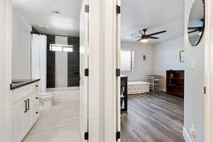 Full bathroom with a ceiling fan, vanity, toilet, shower / bath combination with curtain, and ensuite bath
