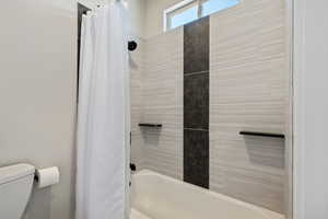 Full bathroom featuring shower / tub combo with curtain and toilet