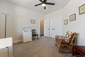 Sitting room with a ceiling fan, carpet flooring, and baseboards