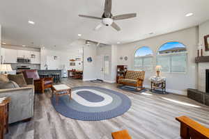 Living room with wood finished floors, baseboards, ceiling fan, recessed lighting, and a tile fireplace