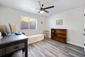 Home office featuring ceiling fan, wood finished floors, and baseboards