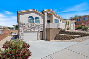 View of front of property with driveway, stucco siding, an attached garage, stone siding, and a tiled roof