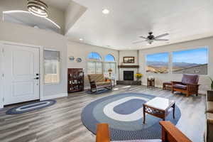 Living area featuring wood finished floors, baseboards, ceiling fan, recessed lighting, and a fireplace