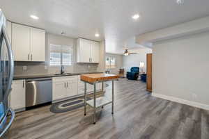 Kitchen with stainless steel appliances, a sink, wood finished floors, decorative backsplash, and recessed lighting