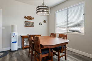Dining area with dark wood-style flooring, a chandelier, and baseboards