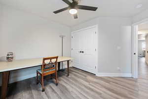 Home office with light wood-style flooring, ceiling fan, and baseboards