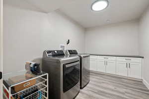 Laundry area with washer and clothes dryer, cabinet space, and light wood-type flooring