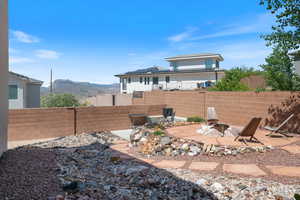 Back of house featuring a fire pit, a fenced backyard, and a mountain view