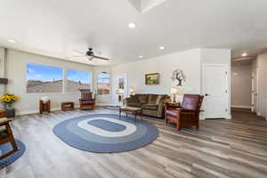 Living room with wood finished floors, baseboards, a ceiling fan, and recessed lighting