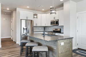 Kitchen featuring appliances with stainless steel finishes, dark countertops, baseboards, dark wood finished floors, and recessed lighting