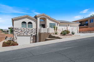 View of front facade with stone siding, stucco siding, concrete driveway, and an attached garage