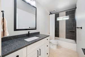 Bathroom featuring vanity, toilet, and shower / bath combination with curtain