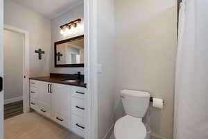 Full bathroom with vanity, toilet, wood finished floors, and baseboards
