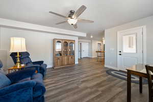 Living room featuring baseboards, a ceiling fan, dark wood-style flooring, and recessed lighting