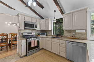 Kitchen featuring stainless steel appliances, a sink, backsplash, a ceiling fan, and pendant lighting
