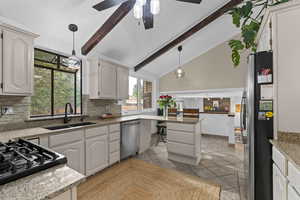 Kitchen featuring appliances with stainless steel finishes, a sink, tasteful backsplash, beam ceiling, and decorative light fixtures