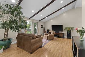Living area with beamed ceiling, light wood finished floors, recessed lighting, baseboards, and high vaulted ceiling