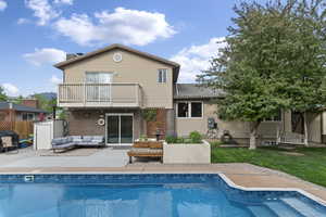 Back of property featuring a balcony, an outdoor living space, a patio, a chimney, and brick siding