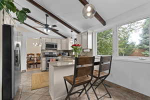 Kitchen featuring stainless steel appliances, a peninsula, decorative backsplash, light tile patterned floors, and a ceiling fan