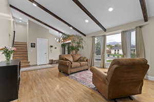 Living area with beamed ceiling, stairs, light wood-style flooring, recessed lighting, and high vaulted ceiling