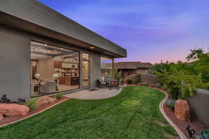 Yard at dusk featuring a yard and a patio area
