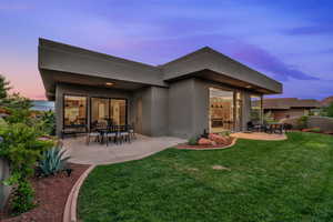 Back of house with a lawn, a patio, and stucco siding