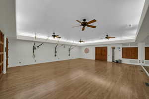 Unfurnished living room featuring light wood finished floors, a tray ceiling, and a ceiling fan