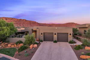 Southwest-style home with driveway, stucco siding, a mountain view, and a garage