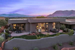 Back of house featuring a mountain view, stucco siding, a patio, and an outdoor living space