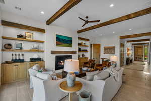 Living area featuring recessed lighting, a lit fireplace, a ceiling fan, beamed ceiling, and built in features