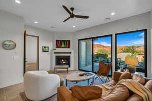 Living room featuring a warm lit fireplace, ceiling fan, recessed lighting, and tile patterned flooring