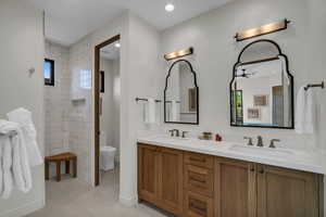 Full bath featuring double vanity, light tile patterned floors, a tile shower, and recessed lighting