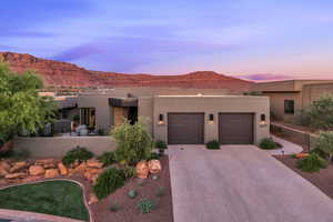 Pueblo-style house featuring a garage, concrete driveway, a mountain view, and stucco siding