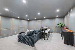 Living area with a decorative wall, carpet flooring, and recessed lighting